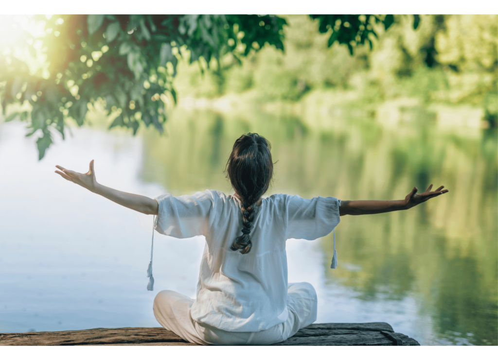 Femme en méditation devant un lac, pratiquant des techniques de relaxation pour optimiser ses chances de tomber enceinte naturellement.