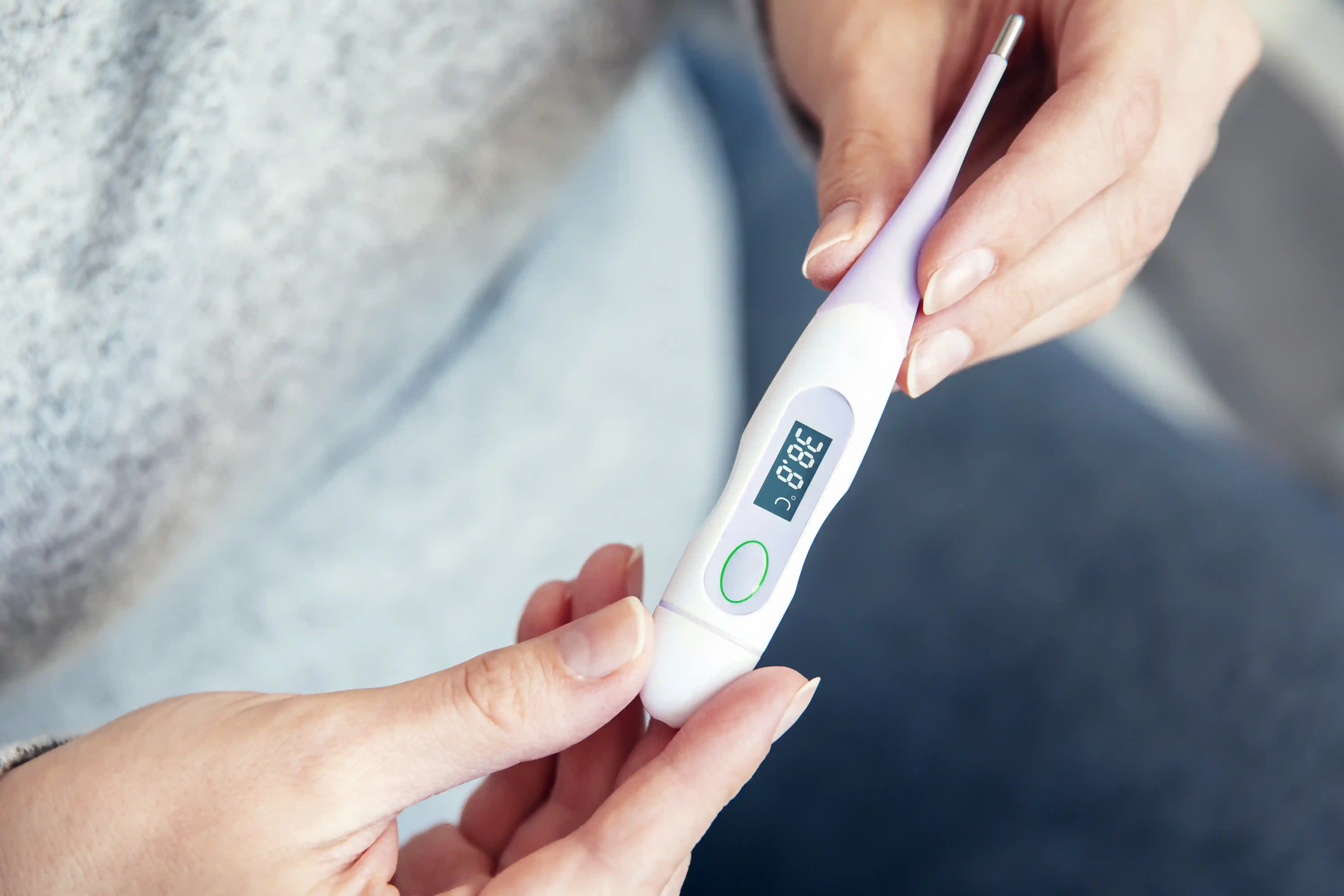 Une personne tient un thermomètre dans ces mains, et se demande pourquoi Utiliser un thermomètre Symptothermie pour suivre sa Fertilité ?