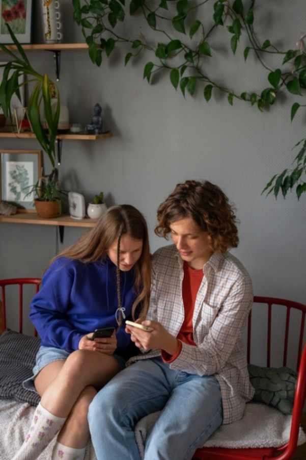 Couple assis sur un fauteuil, explorant ensemble des informations sur la contraception naturelle sur le téléphone.