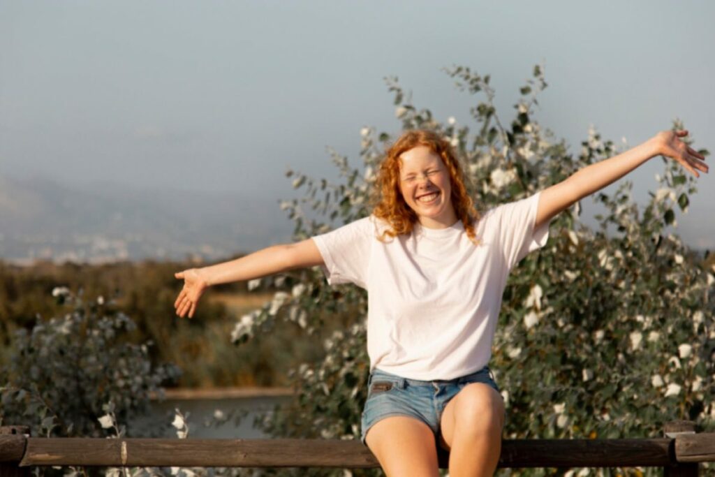 Femme heureuse et souriante, les bras levés en signe de liberté et de bien-être, illustrant l'épanouissement grâce à l'allaitement et à la contraception naturelle.