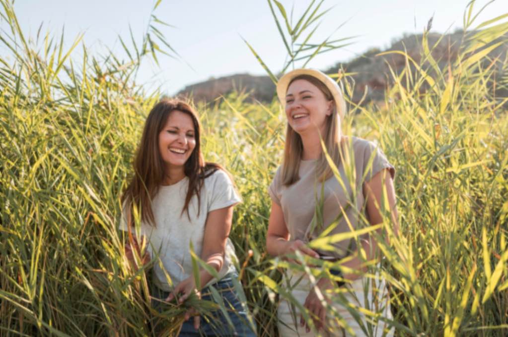 Deux femmes souriantes et épanouies dans la nature, symbolisant l'harmonie avec leur corps, en lien avec la fertilité, le cycle menstruel et la symptothermie.