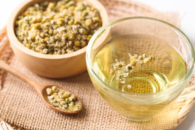 tasse d'une tisane à la Camille et sa plante pour réduire les douleurs de règles